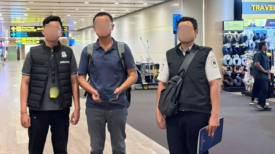 Petugas Inteldakim Imigrasi Imigrasi Ngurah Rai mengawal proses deportasi satu WNA asal Korea Selatan (tengah) yang wajahnya disamarkan di Bandara Ngurah Rai, Kabupaten Badung, Bali, Selasa (27/1/2026). (Imigrasi Ngurah Rai)