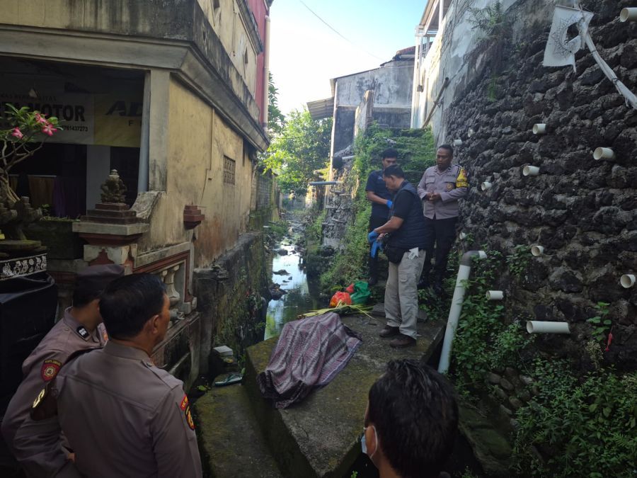 Petugas kepolisian mengamankan lokasi penemuan jenazah I Made Sukarsa di sungai Tukad Guming. Korban diduga jatuh terpeleset saat hendak ke pasar. (foto/hes)