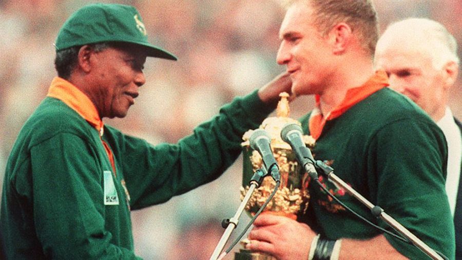 Kapten Springbok Francois Pienaar menerima Piala Dunia Rugbi dari Presiden Afrika Selatan Nelson Mandela di Ellis Park, Johannesburg, pada 24 Juni 1995. Afrika Selatan memenangkan pertandingan final melawan Selandia Baru dengan skor 15-12 setelah perpanjangan waktu. (Philip Littleton/AFP/Getty Images)