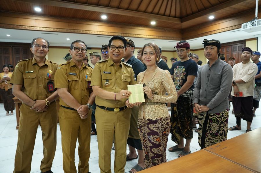 Bupati Badung I Wayan Adi Arnawa saat menyerahkan buku rekening tabungan kepada 26 Sekaa dan Komunitas Seni yang akan menjadi Duta Kabupaten Badung pada PKB XLVIII Tahun 2026, di Puspem Badung, Bali, Senin (13/4/2026). (foto/adi)