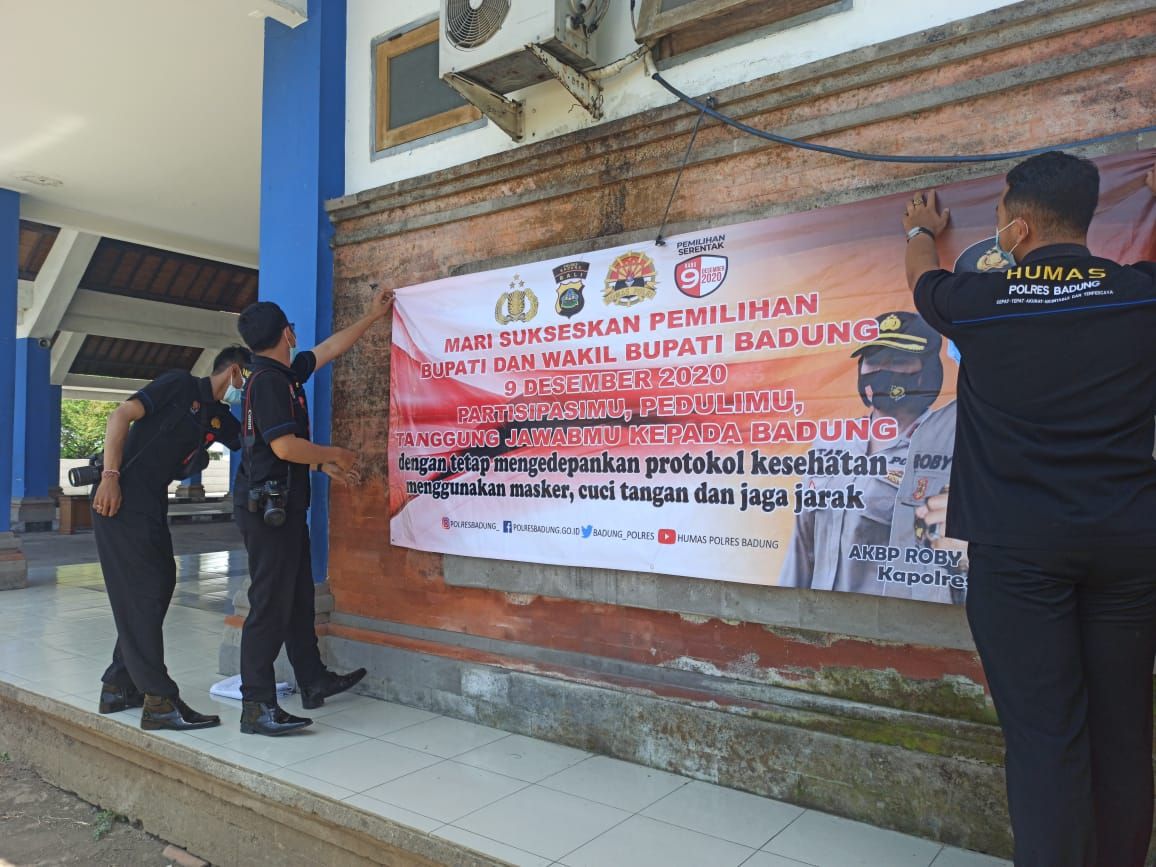 podiumnews.com-Polres Badung Pasang Baliho Tertib Prokes Saat Pencoblosan Pilkada