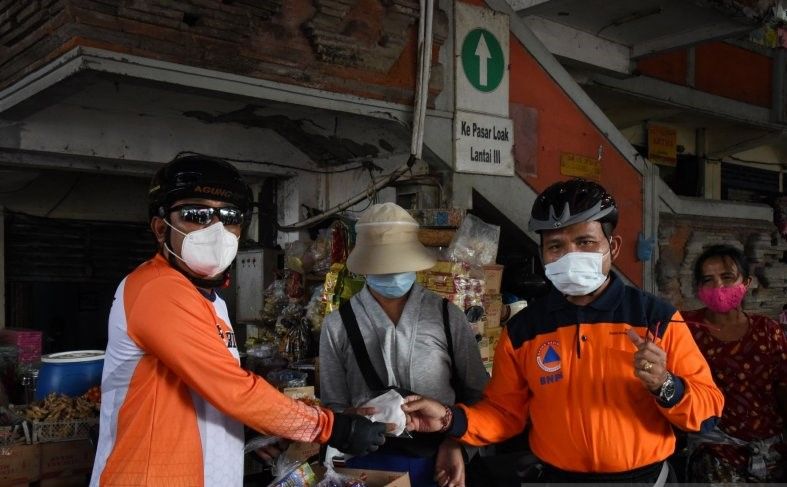 podiumnews.com-KPU Bali dan BPBD Bersepeda Bagikan Masker ke Pedagang Pasar
